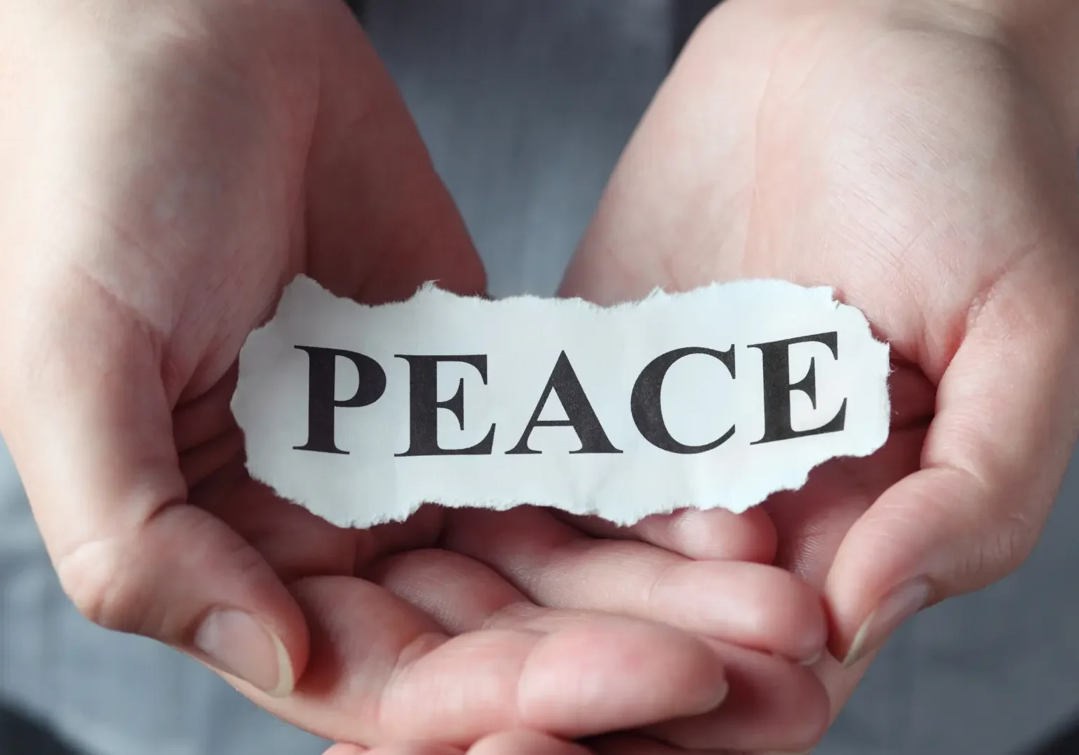 Peace-written-on-note inherited House Solutions for a Peaceful Resolution – Hands Holding a Torn Paper with 'Peace' Written on It